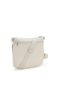 Beige crossover taske med justerbar rem, frontlomme med lynlås og en lille fluffy pom-pom nøglering på hvid baggrund.
