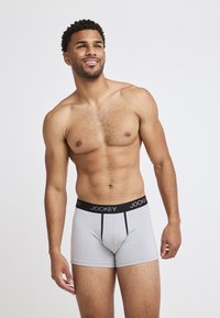 Gray boxer briefs with a black elastic waistband featuring the "Jockey" logo, made from soft, stretchy material. Design includes contrasting lines.