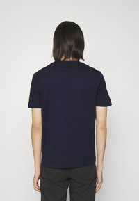 Tummansininen lyhythihainen t-paita pyöreällä kauluksella, sileä rakenne ja suora helma. Ei näkyviä logoja tai kuvioita.