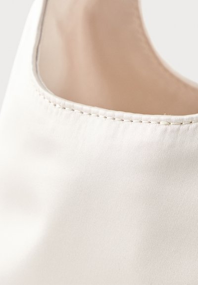 Κοντινή λήψη λείου λευκού δερμάτινου άνω μέρους παπουτσιού με εμφανείς ραφές κατά μήκος της άκρης και μπεζ εσωτερική επένδυση.