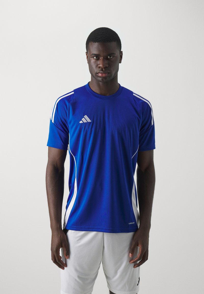 Blå atletisk skjorte med hvite detaljer og korte ermer, med rund hals og en liten logo på brystet. Modellen har på seg hvite shorts.