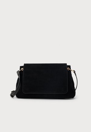 Zwarte suède crossbodytas met een flap aan de voorkant en verstelbare leren band tegen een effen lichtgrijze achtergrond.