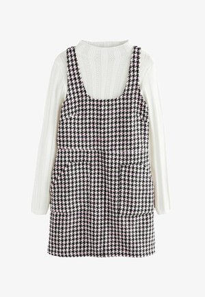 Sorte og hvide houndstooth-kjole med lyserøde accenter, med firkantet udskæring og to forlommer. Bæres over en hvid ribbede sweater.