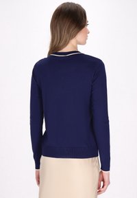 Pulover bleumarin cu mâneci lungi, decolteu rotund și accente crem la guler și manșete. Textură netedă și design ajustat.
