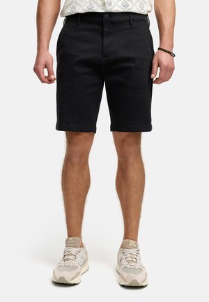 Zwarte katoenen shorts met een rechte snit, voorzakken en knoopsluiting. Gemaakt met beige sneakers en een gemusterd shirt.