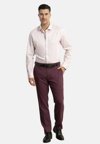 Camisa de botones de color rosa claro con un patrón sutil, combinada con pantalones de vestir burdeos y zapatos negros, y un cinturón negro.