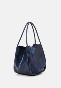 Marinblå läderhandväska med texturerad lapptäckedesign, två flätade handtag och en slät yta. Har en avslappnad silhuett.