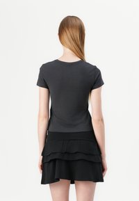 Gray short-sleeve t-shirt with a round neck, paired with a black layered ruffled skirt. The fabric appears soft and smooth.