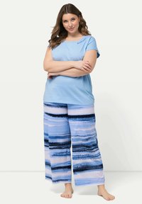 Blå bomulls-T-shirt med broderi av "god natt", matchad med vida byxor med horisontella blå och vita ränder.