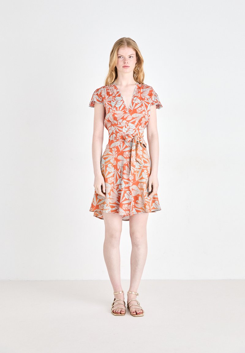 Ärmelloses Wickelkleid in Orange, mit Blumenmuster in Blau und Weiß. Der Rock ist ausgestellt, und ein passender Gürtel betont die Taille.