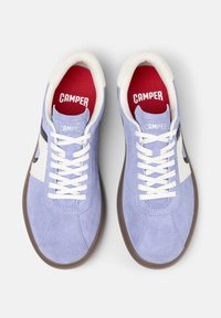 Light purple suede sneakers with white accents, round toe, flat brown rubber sole, and white laces. Red interior with “CAMPER” branding.