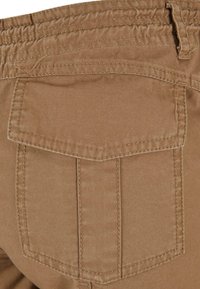 Beige bombažne cargo hlače z zadnjim žepom z preklopom in dvema vertikalnima šivoma. Mehka tekstura z gladko površino.
