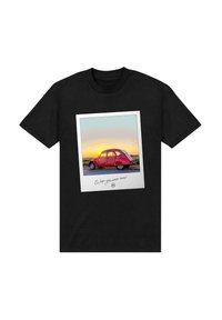 Svart t-shirt med grafiskt tryck av en vintage röd bil i en vit Polaroidram med solnedgångsbakgrund, med text nedanför.