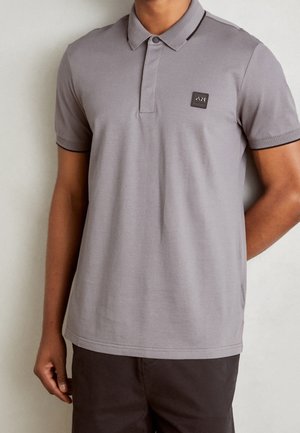 Grå poloshirt med slank pasform, korte ærmer, ribstrikkede manchetter, tre-knaps knappelukning og et lille logoemblem på brystet.