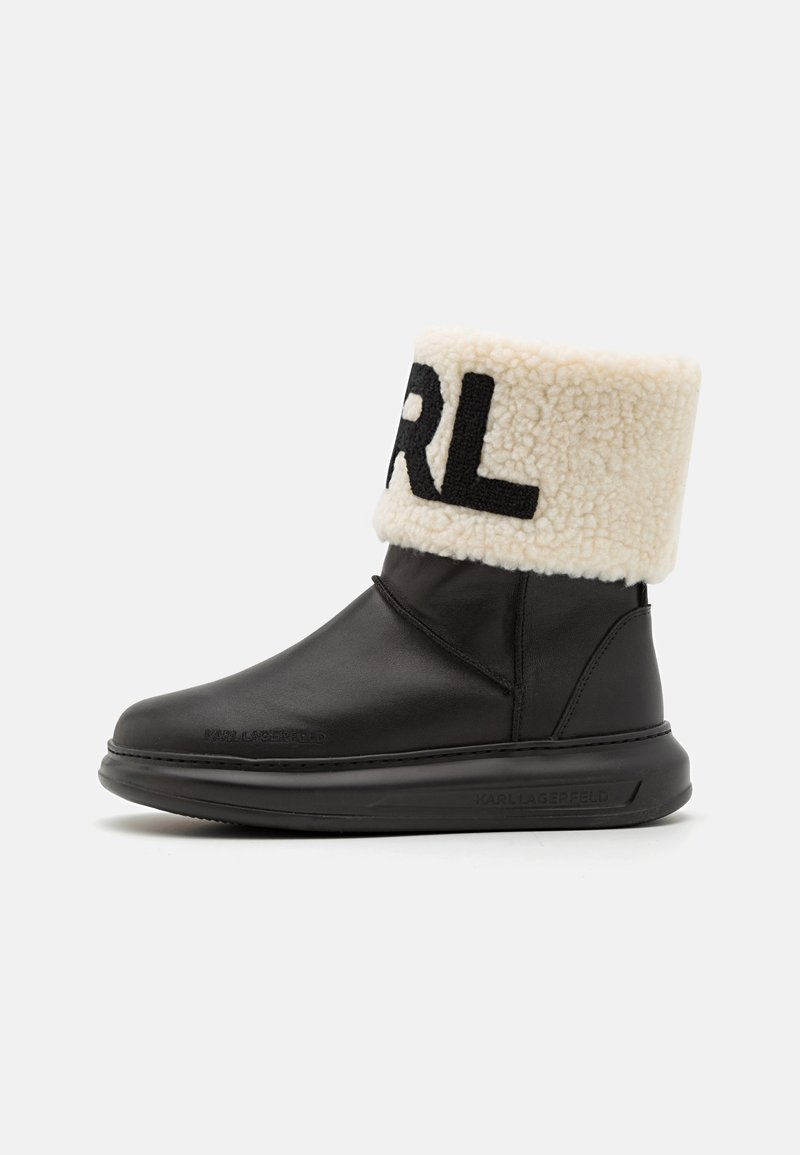 Black leather ankle boot with a plush cream shearling fold-over cuff featuring "Karl" in black lettering. Rubber sole, sleek design.