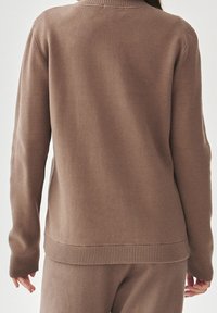 Maglione marrone con colletto e polsini a coste, caratterizzato da una texture morbida e una vestibilità rilassata, visto da dietro.