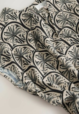 Leinenhemd mit schwarzem botanischem Muster auf beigem Hintergrund, mit lässiger Passform und weicher Textur.