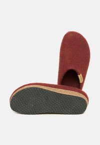 Red felt slipper with open back, cork midsole, and textured black rubber outsole. Features a small logo tag on side.