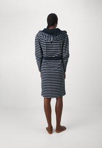 Robe a strisce con cappuccio in blu navy e bianco, la texture del tessuto è morbida. Presenta una vita con lacci e polsini aderenti, che arriva fino a metà polpaccio.