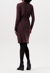 Mörkröd stickad klänning med långa ärmar, elastisk midja och sidoslits. Stylerad med svarta ankelstövlar och ogenomskinliga strumpbyxor.