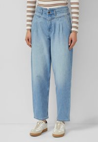 Jasnoniebieskie jeansy z denimu z wysokim stanem, plisowaną przednią częścią i prostymi nogawkami. Do tego beżowe trampki i pasiasty top z długim rękawem.