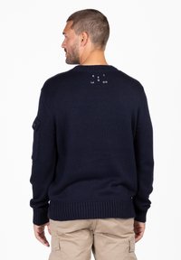 Marineblauer Strickpullover mit Rundhals, gerippten Bündchen und Saum, aus strukturiertem Stoff und mit einem kleinen Logodetail auf dem oberen Rücken.