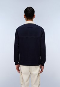 Camisa de manga larga en color marino con un cuello beige en contraste, de textura suave y corte recto. La camisa tiene mangas tipo raglán.