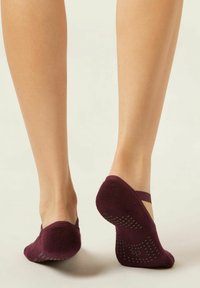 Burgundy ankle socks with a textured surface and dotted grip on the soles; features a slender strap around the upper foot.