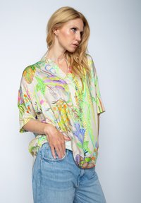 Kurzärmliges, lockeres Shirt aus leichtem Stoff, das lebhafte florale und abstrakte Drucke in Grün-, Pink- und Blautönen mit einem V-Ausschnitt aufweist.