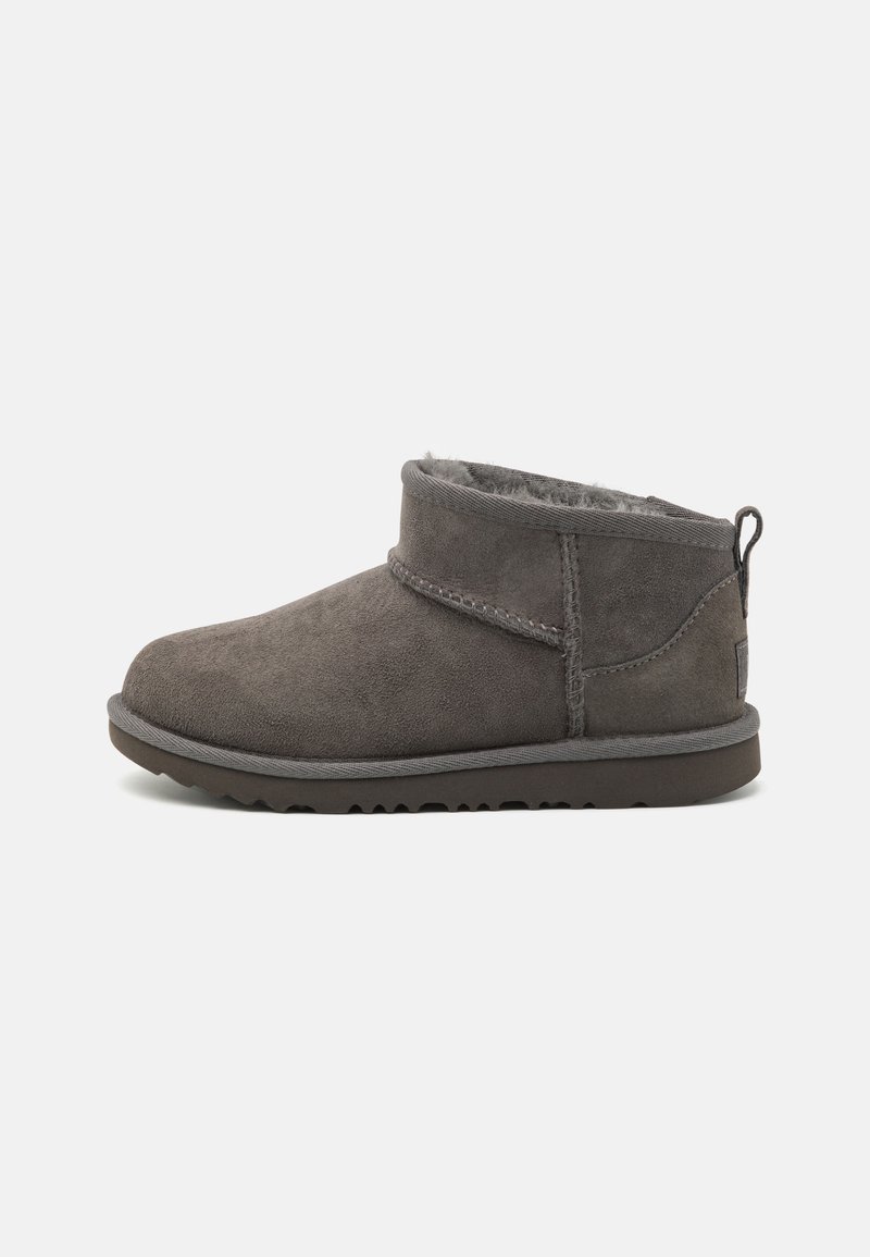 Botas de tobillo de ante gris con un suave forro de piel de pelo, puntera redondeada, detalles cosidos y una lengüeta en el talón. Suela de goma con textura.
