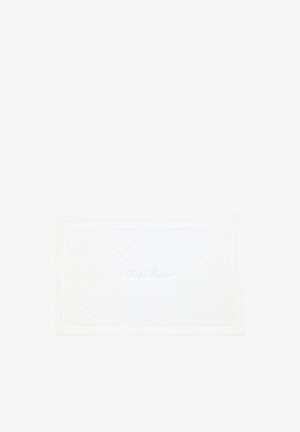 Tapis de bain rectangulaire blanc matelassé à motif losange et broderie subtile au centre, posé sur un fond blanc uni.