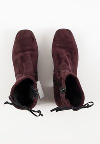 Bottines en daim bordeaux avec un bout carré et des zips sur le côté. Elles présentent une surface texturée et des lacets ajustables pour un meilleur maintien.