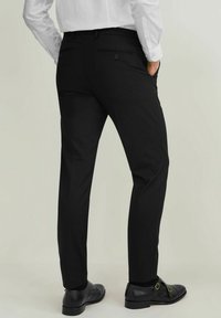 Svarta formella byxor med skräddarsydd passform, mjuk textur, två bakfickor och diskreta ränder, tillsammans med eleganta svarta skor.