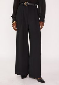 Zwarte broek met wijde pijpen en een hoge taille, voorzien van scherpe vouwen, een gladde textuur en een zwarte riem met een ronde metalen gesp.