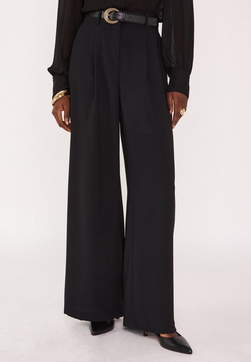 Zwarte broek met wijde pijpen en een hoge taille, voorzien van scherpe vouwen, een gladde textuur en een zwarte riem met een ronde metalen gesp.