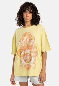 Gul oversized T-shirt lavet af bomuld, med et farverigt grafisk design med sol- og blomster mønstre. Korte ærmer og rund halsudskæring.