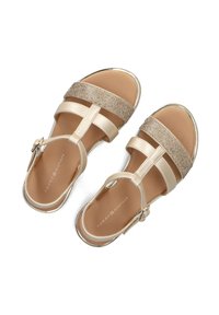 Sandali beige con cinturini in vernice lucida e una fascia metallica testurizzata. Chiusura con fibbia regolabile, suola piatta e soletta imbottita.