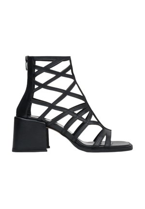 Black high-heeled sandal with a strappy design, featuring a block heel and zip closure at the back. Made from leather with a smooth texture.
