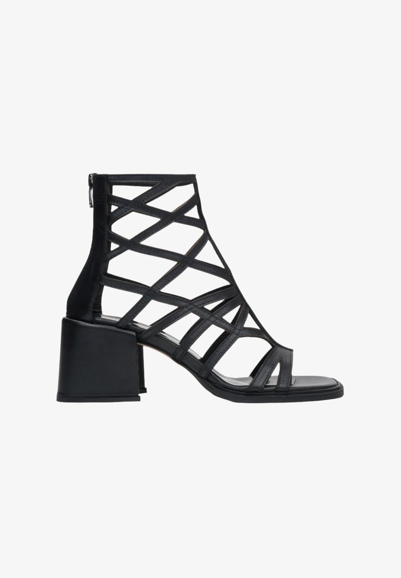 Czarna sandałki na wysokim obcasie z paskami, z blokowym obcasem i zapięciem na zamek z tyłu. Wykonane ze skóry o gładkiej fakturze.