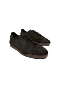 Sneaker in scamosciato marrone con finitura testurizzata, punta arrotondata e design con lacci. Suola in gomma con accenti discreti lungo i bordi.