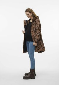 Vattentålig leopardmönstrad kappa i brunt och svart, lång design med huva, elastiska ärmslut, kombinerad med blå skinny jeans och bruna anklarstövlar.