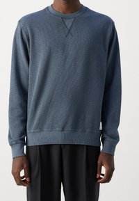 Blauwe crewneck sweatshirt van textuurstof, met ribgebreide manchetten en zoom, voorzien van een klein label aan de zijkant en een ontspannen pasvorm ontwerp.