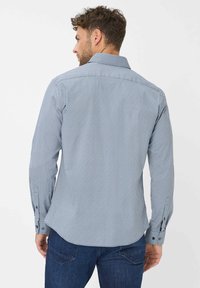 Camicia a maniche lunghe a righe blu e bianche con colletto classico, polsini con bottoni e vestibilità su misura. Il tessuto è liscio con una sottile texture.
