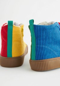 Bocanci cu glezna din catifea colorată în roșu, galben, albastru și verde, având panouri texturate contrastante, cu o talpă zimțată de culoare maro și tab-uri din material.