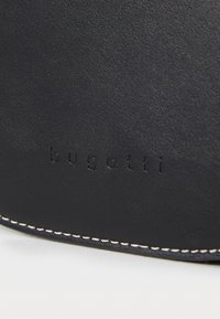 Billetera de cuero negro con el logotipo "bugatti" en relieve, costura blanca a lo largo del borde, superficie texturizada y forma redondeada.