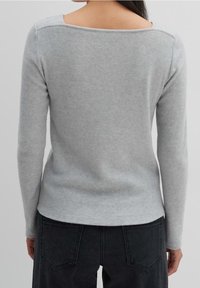 Grå långärmad tröja med vid halsringning, tillverkad av mjukt ribbat material, med en figurnära design och subtil textur på baksidan.