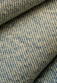 Jeansstoff in Creme- und Blautönen, mit einer strukturierten Webart, diagonaler Rippung und subtile Farbvariationen.