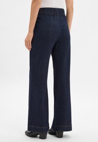 Ciemnoniebieskie spodnie dzwony z elastycznym paskiem w talii i prostym krojem, z wykończeniem z kontrastowym przeszyciem.