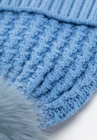 Modrá pletená čepice s texturovaným vzorem, nahoře s světle modrým umělým kožíškovým bambulí a žebrovaným lemem.
