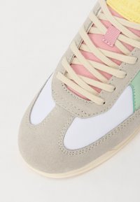 Graue Wildledersneaker mit rosa und grünen Akzenten, weißen Overlays und beigen Schnürsenkeln. Weicher Textur mit runder Zehenpartie und Gummisohle.